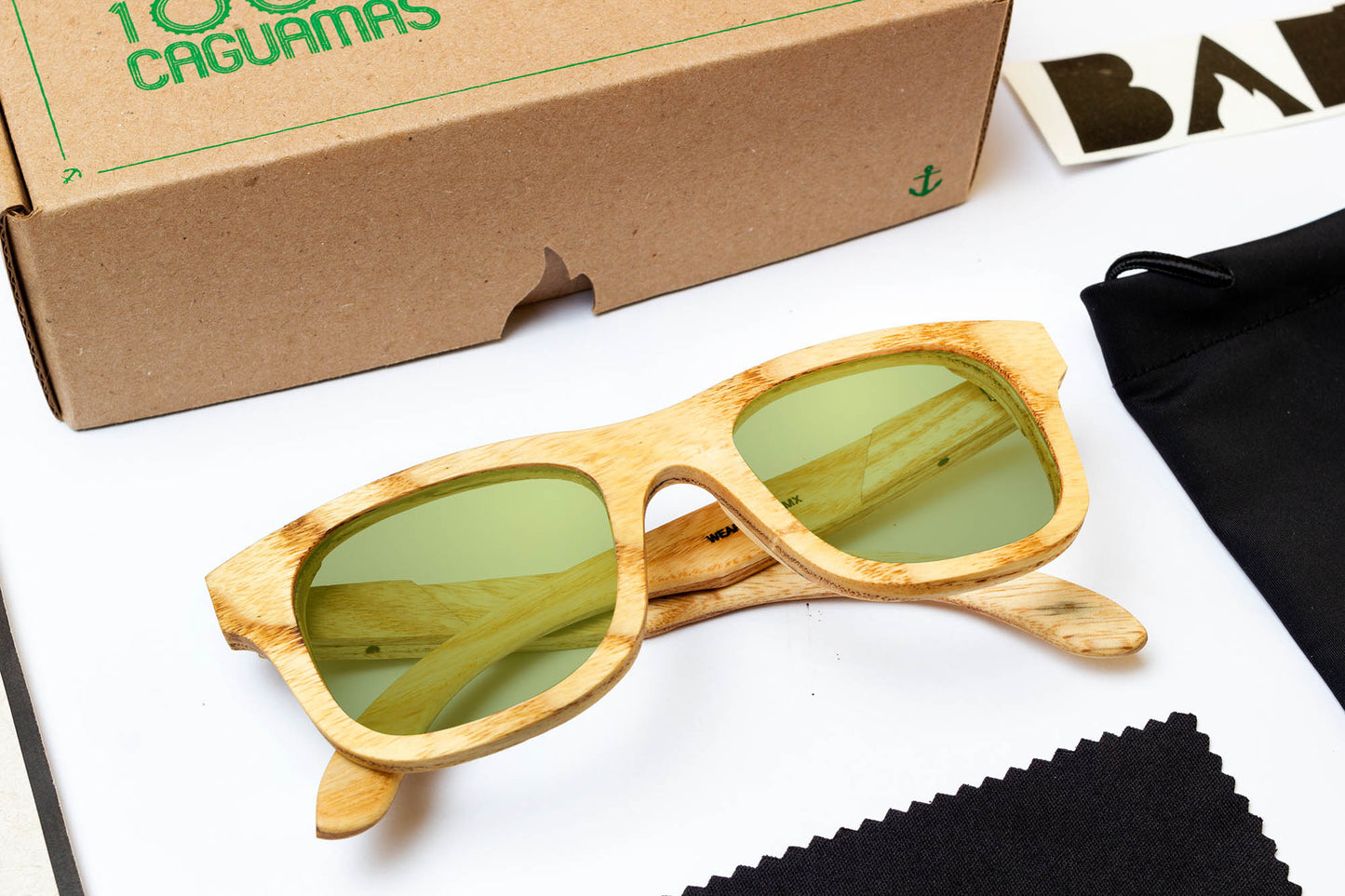 zoom del kit de lentes 1000 caguamas de Bang, detalle de empaque, sticker morral, lentes y microfibra de limpieza, fondo blanco