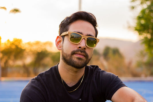 Modelo hombre con lentes 1000 caguamas de Bang, edición especial, mica verde polarizada, lentes de madera, parque, fondo con bokeh