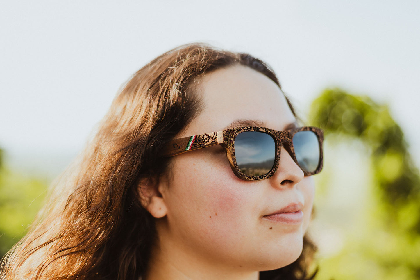Modelo mujer usando lentes mexa, marca bang, fabricados con madera grabada y artesanía huichol, micas polarizadas, lentes conmemorativos México