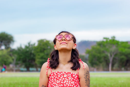 Modelo mujer en parque con lentes de sol bang, madera, corazón, mica rosa