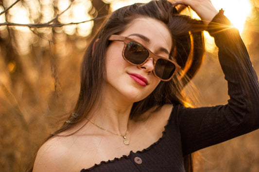 Modelo mujer usando los Lentes de Madera Bang, modelo Nativo Lateral, micas polarizadas, atardecer, fondo con bokeh