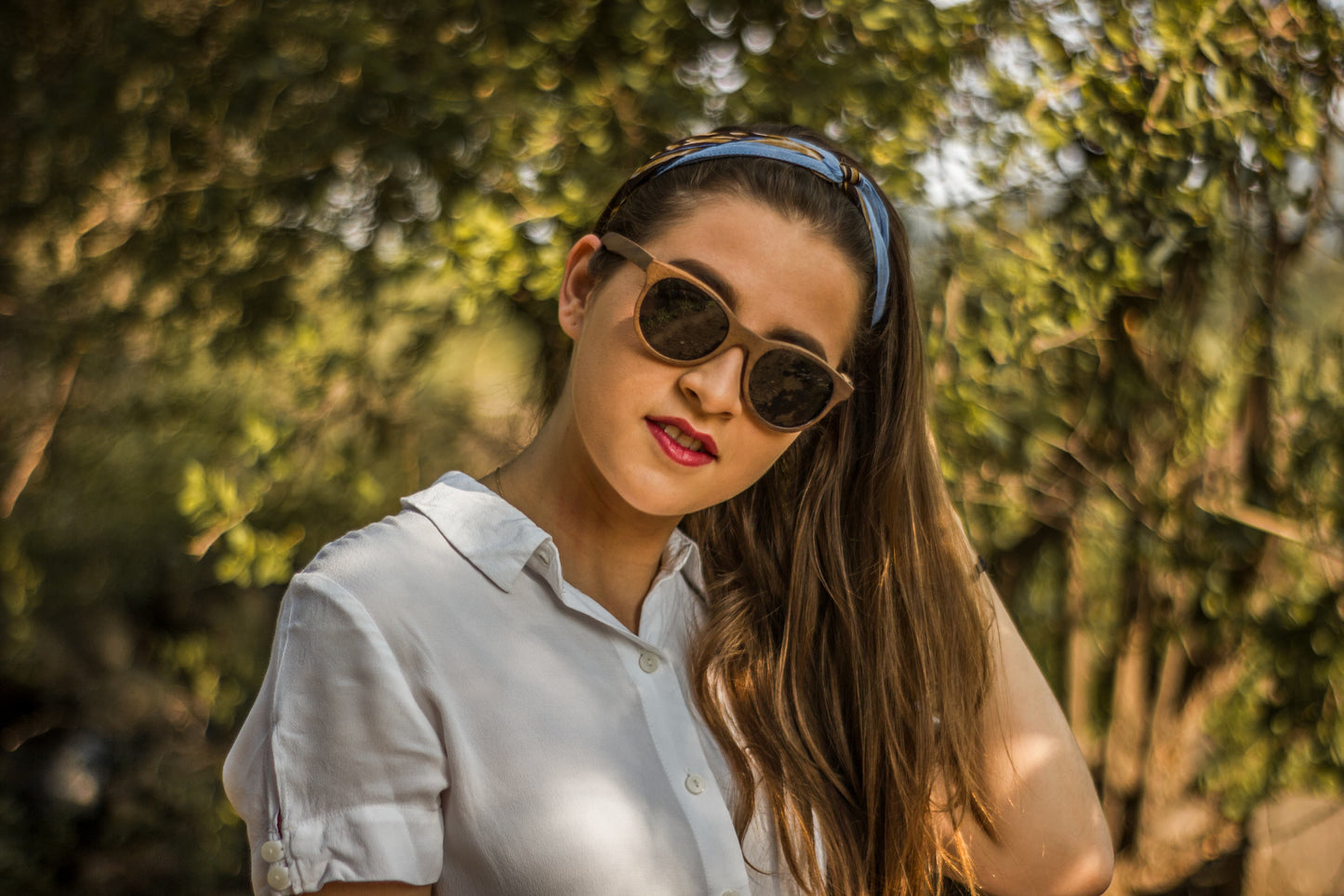Modelo mujer con lenes de sol, modelo huitzil, micas humo polarizadas, fabricados en madera, fondo de naturaleza con bokeh