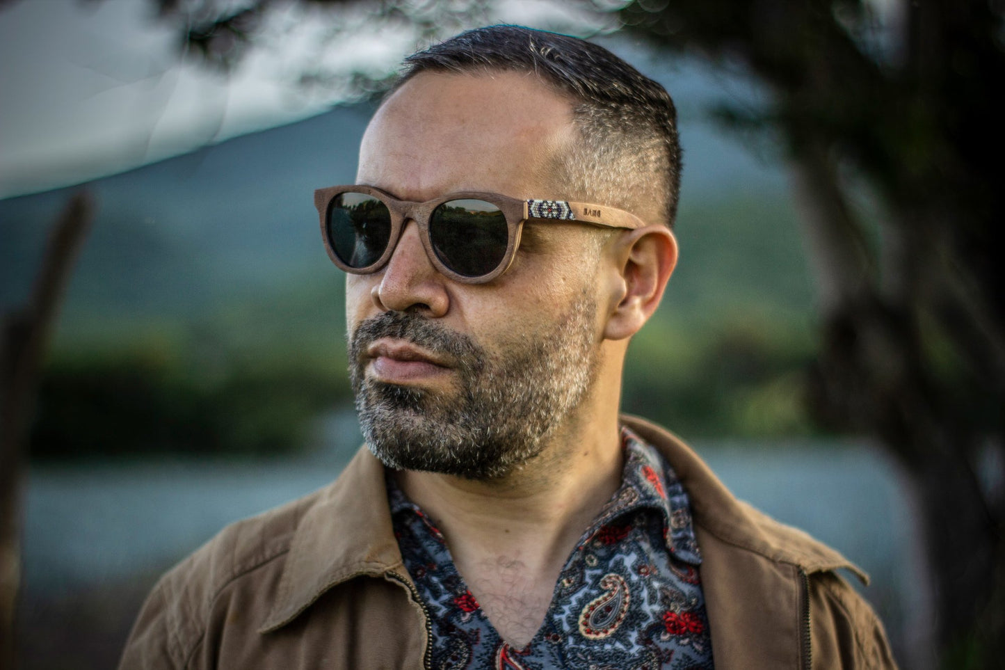 Modelo hombre con lentes hikuri plata, lente oscuro con mica polarizada, intervenidos con artesanía huichol,
fondo de naturaleza bokeh