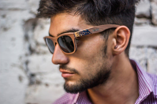 modelo hombre con lentes huicholes de madera, micas de sol polarizadas, colores oro con azul tornasol, foto lateral