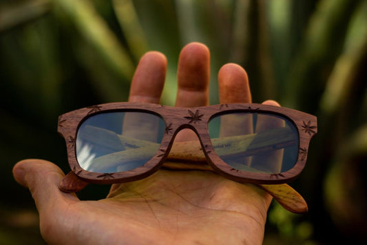 Grabado de cannabis en lentes paradise de bang, mano sosteniendo los lentes y vegetación de fondo, micas verdes polarizadas