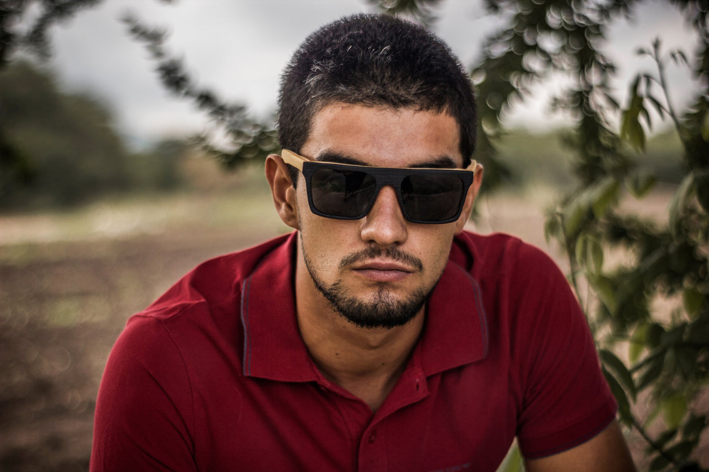 Modelo hombre con lentes de madera Bang, modelo jaguar, micas oscuras polarizadas, fondo de naturaleza con bokeh