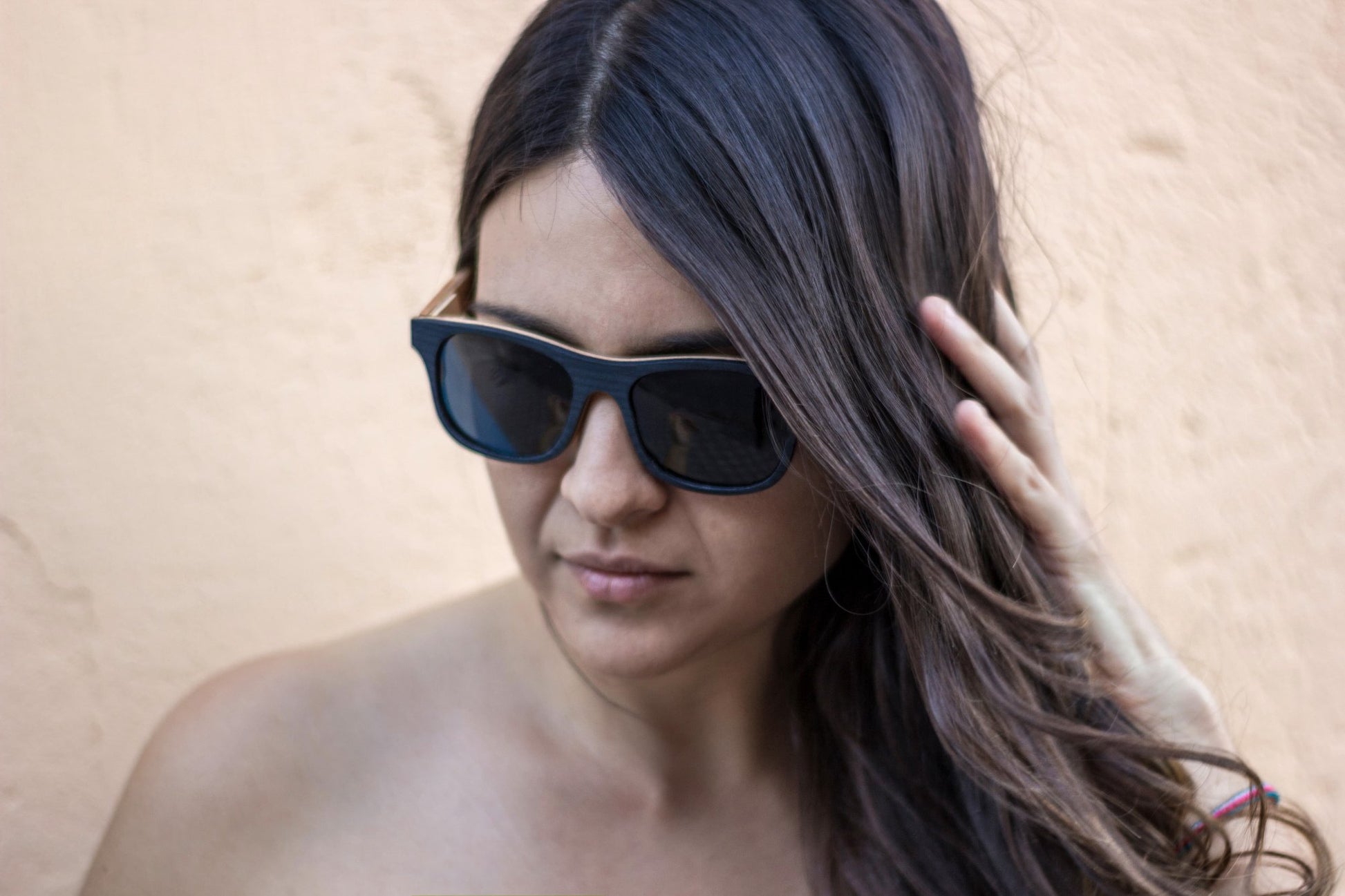 Modelo mujer usando lentes de sol bang, fabricados con madera, modelo nativo ébano, fondo color crema