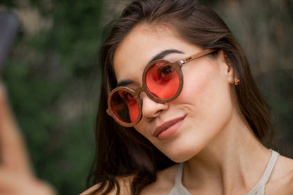 Mujer usando Lentes de madera Bang, modelo Pink, micas rosas polarizadas, fondo blureado
