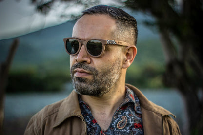 Modelo hombre con lentes hikuri plata, lente oscuro con mica polarizada, intervenidos con artesanía huichol, 
fondo de naturaleza bokeh