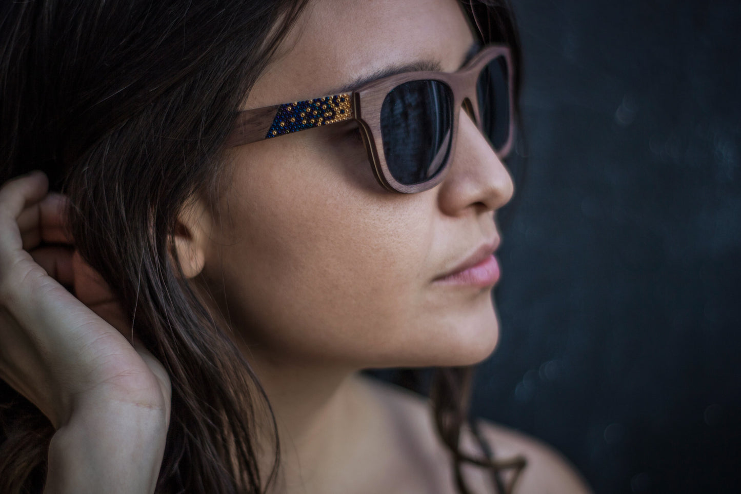 Modelo mujer con lentes huicholes de madera, micas de sol polarizadas, colores oro con azul tornasol, foto lateral